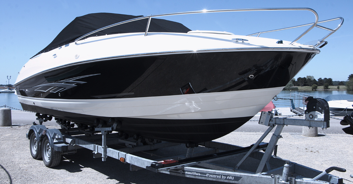 White and black motorboat on a trailer, with a blue sky backdrop.