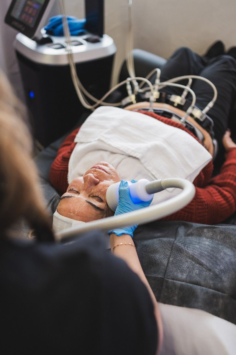 A woman is laying on a bed getting a facial treatment.