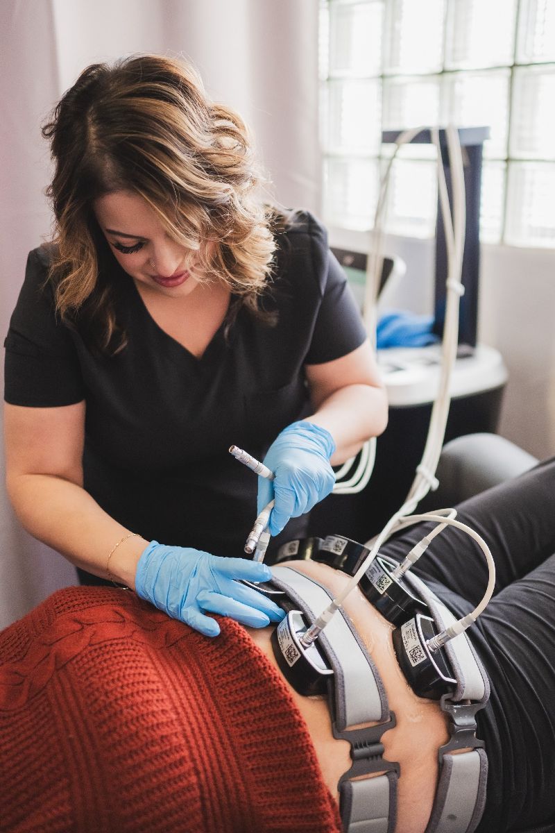 A woman is using a machine on a woman 's belly.