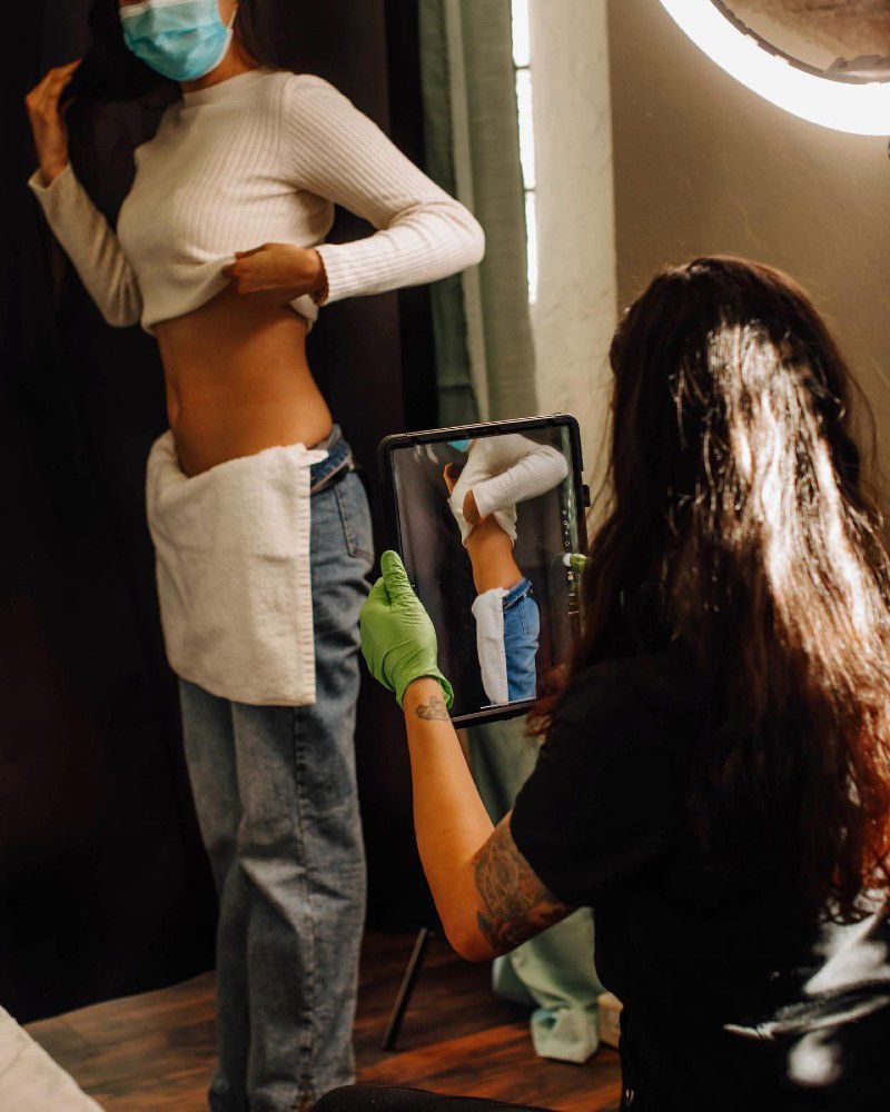 A woman wearing a mask is taking a picture of herself in a mirror.