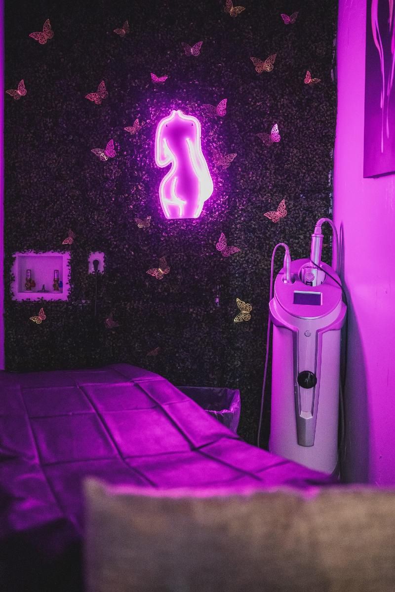 A purple room with a neon sign on the wall and a machine.