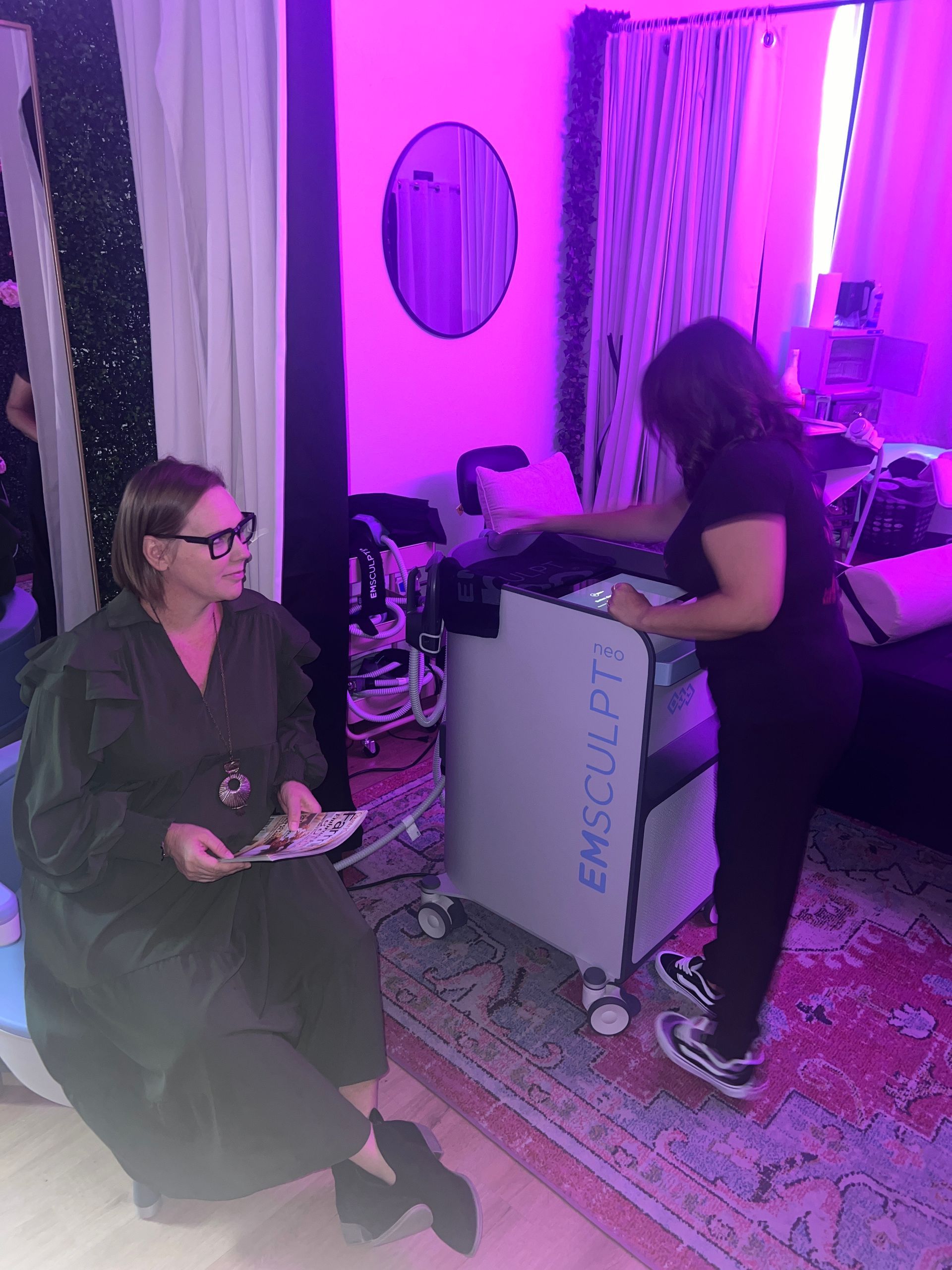 A woman is sitting on a bean bag chair in front of a machine.