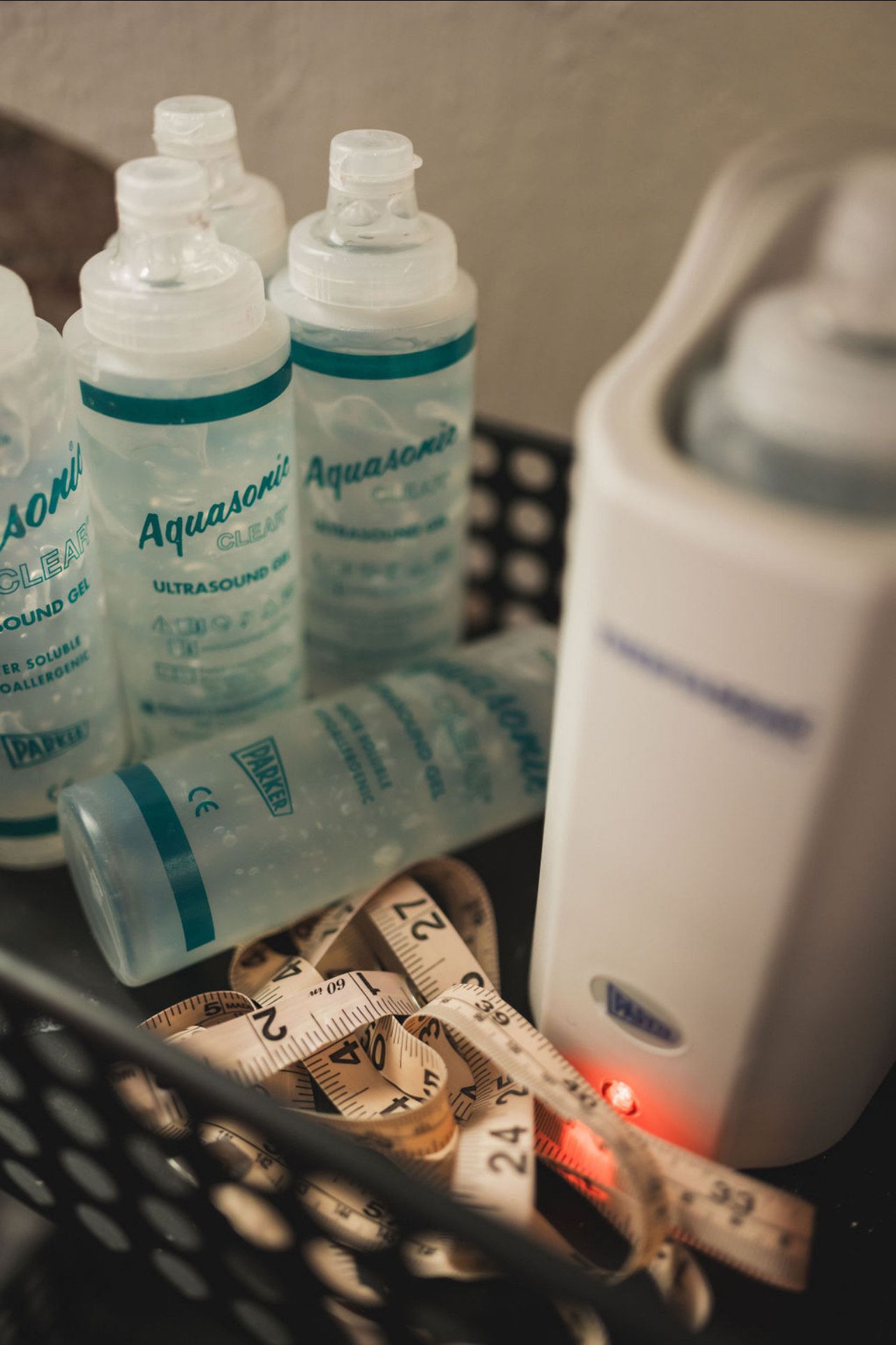 A bunch of bottles are sitting on a table next to a measuring tape.