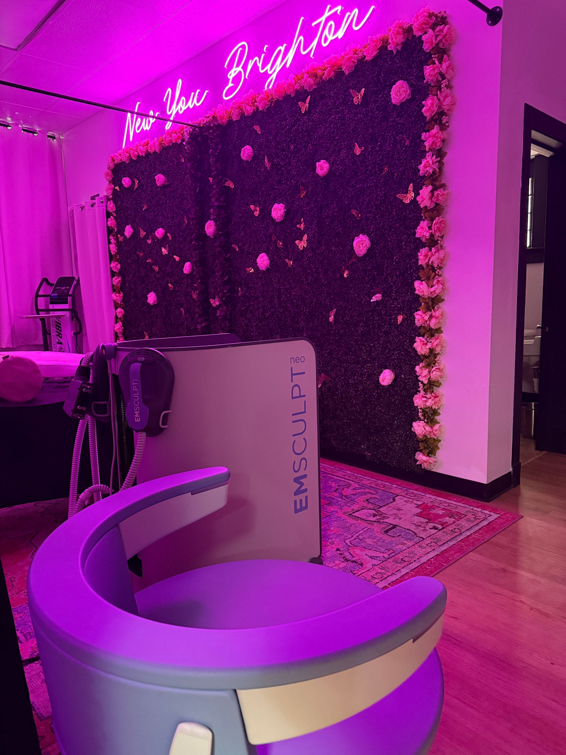 A purple chair in front of a neon sign that says now you brighten