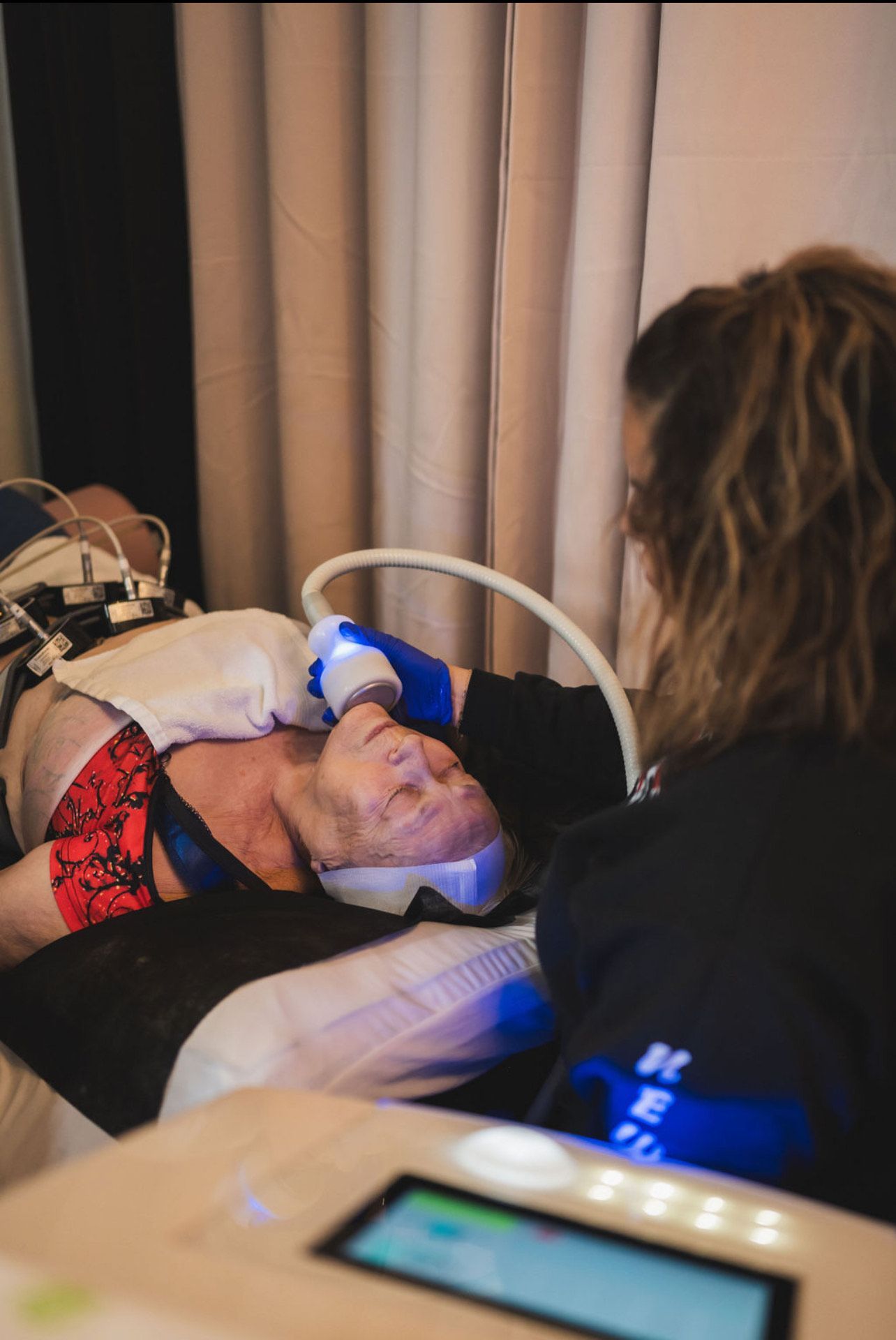A woman is laying on a bed getting a facial treatment.