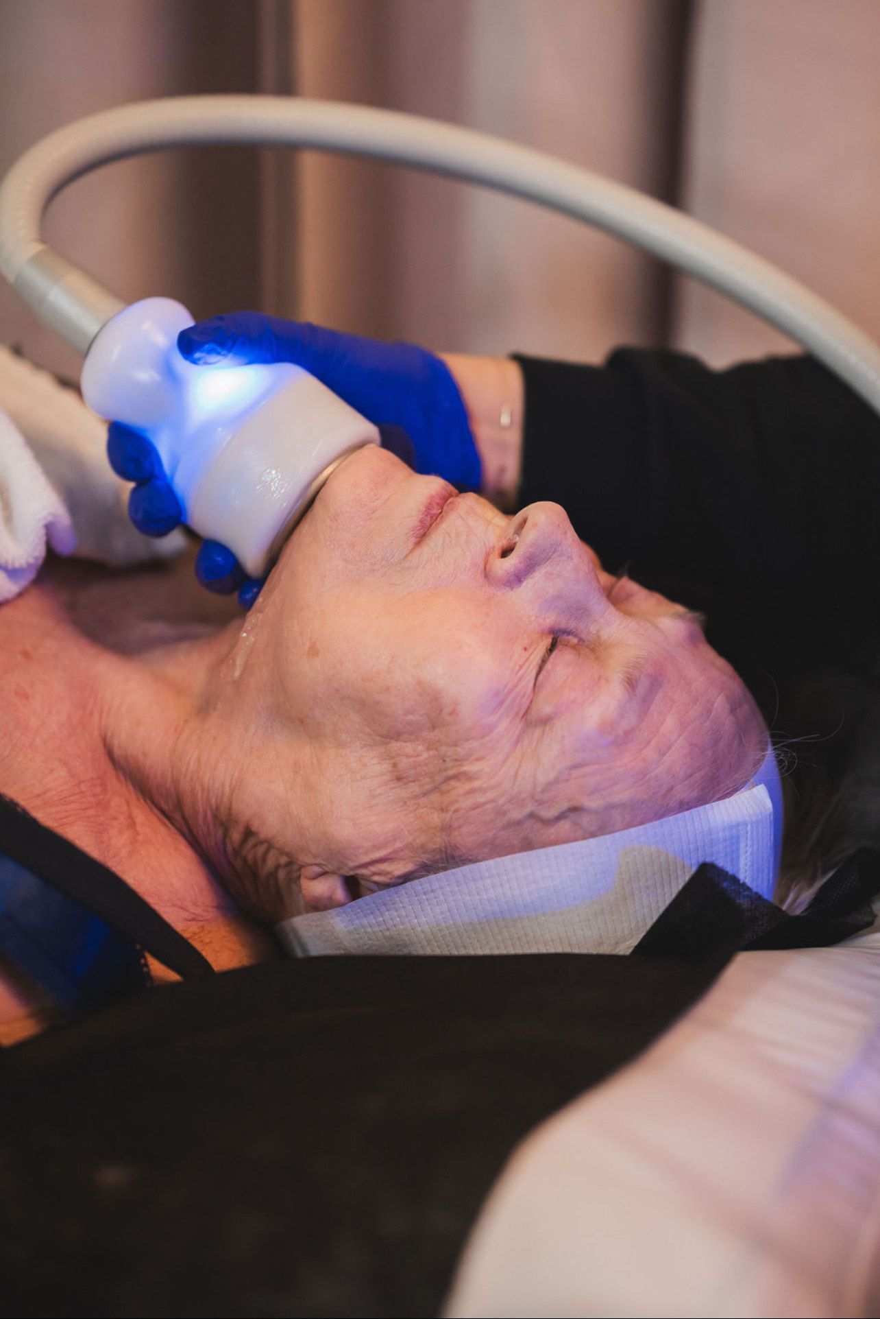 A woman is laying on a bed getting a facial treatment.