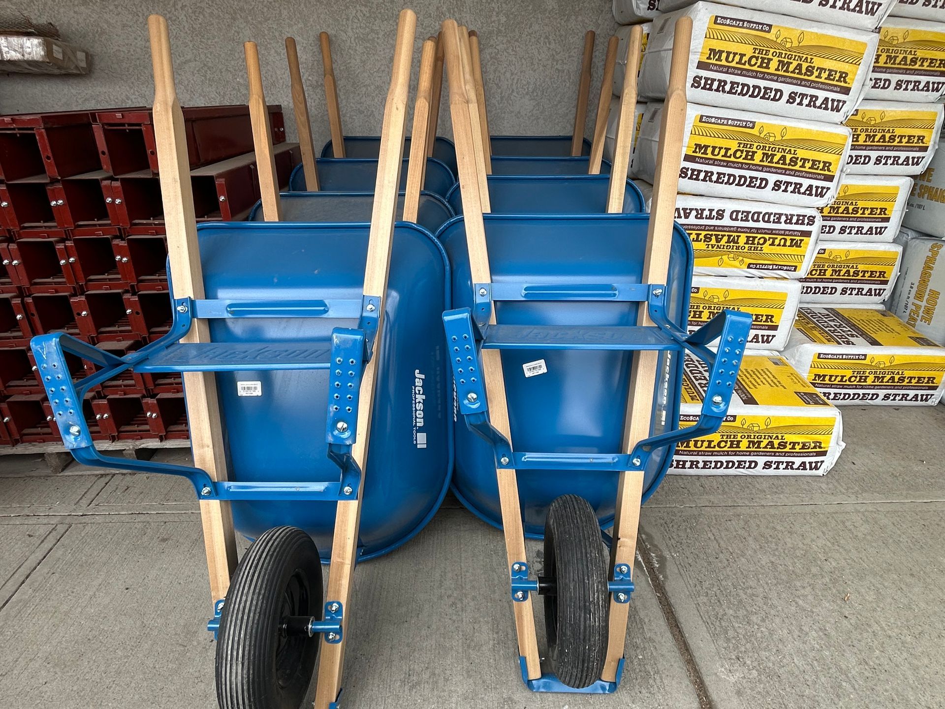 A bunch of blue wheelbarrows are stacked on top of each other