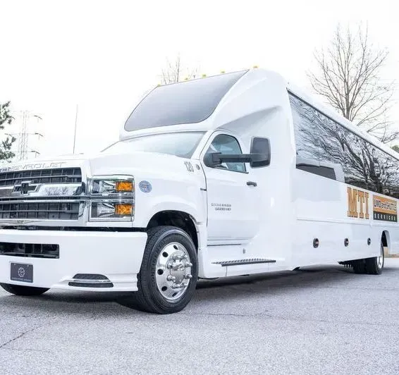 White luxury shuttle bus with tinted windows parked outdoors on a bright day