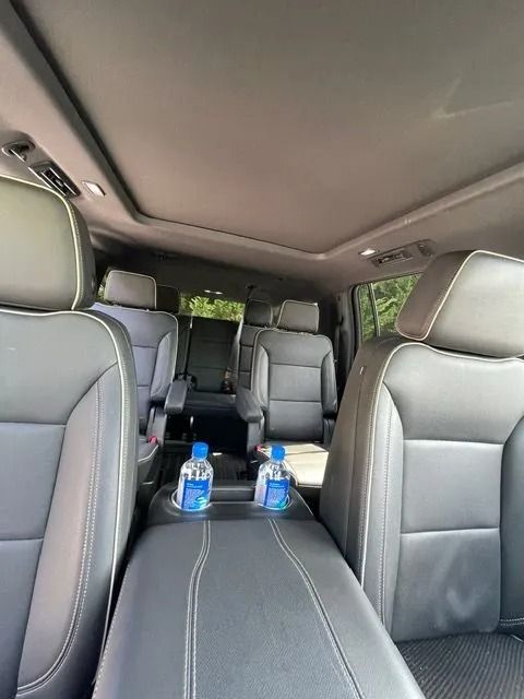Interior of a vehicle featuring dark grey leather seats, a center console with two water bottles, and a sunroof.
