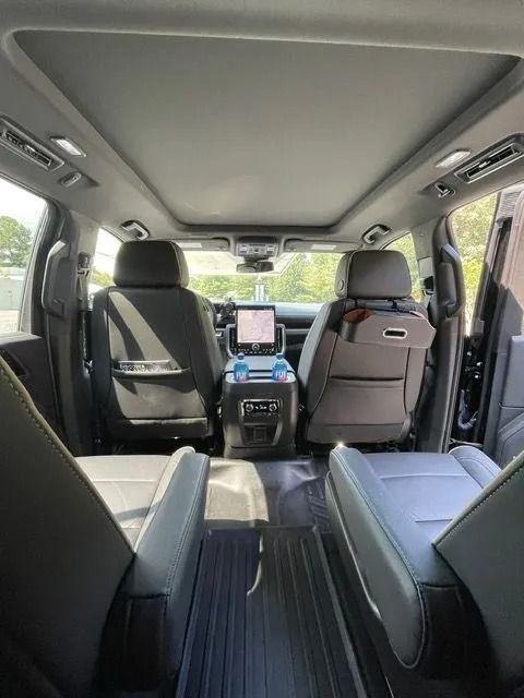 Interior view of a spacious SUV featuring captain's chairs, a panoramic sunroof, and a rear center console with a display.