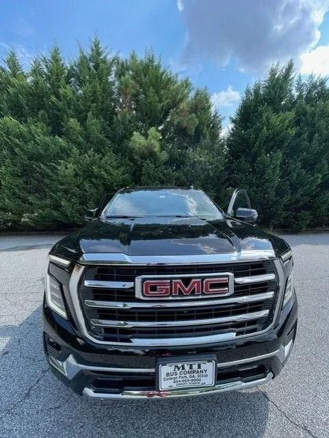 A black GMC pickup truck parked in an outdoor lot with green trees in the background.