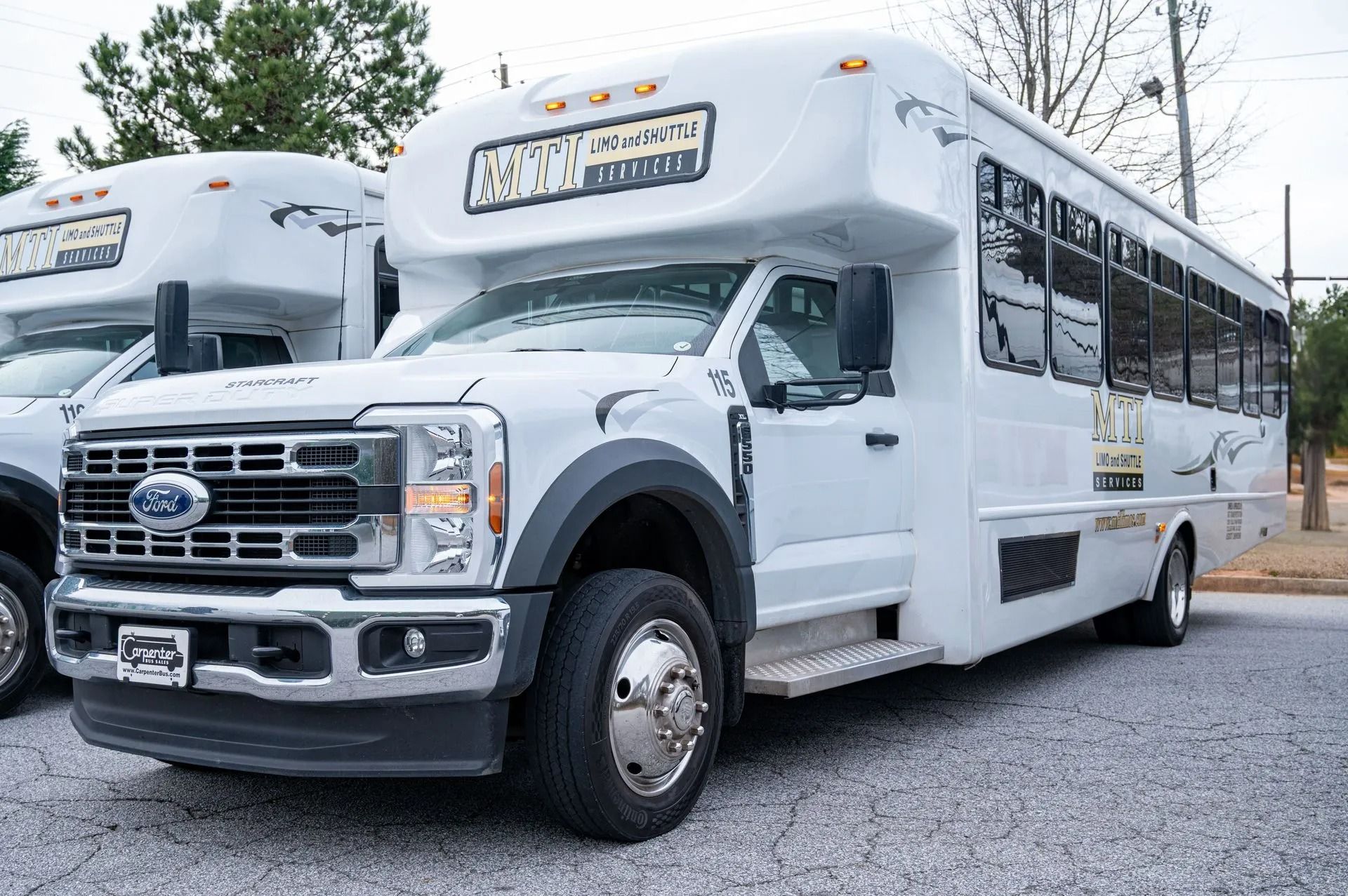 A white Ford shuttle bus parked on a gravel lot, viewed from the front passenger side.