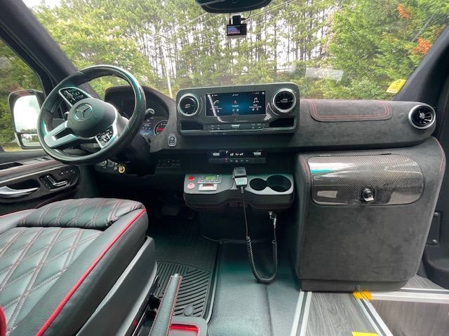 A driver's view from inside a luxury Mercedes-Benz van, featuring black quilted leather seats and a digital dashboard.