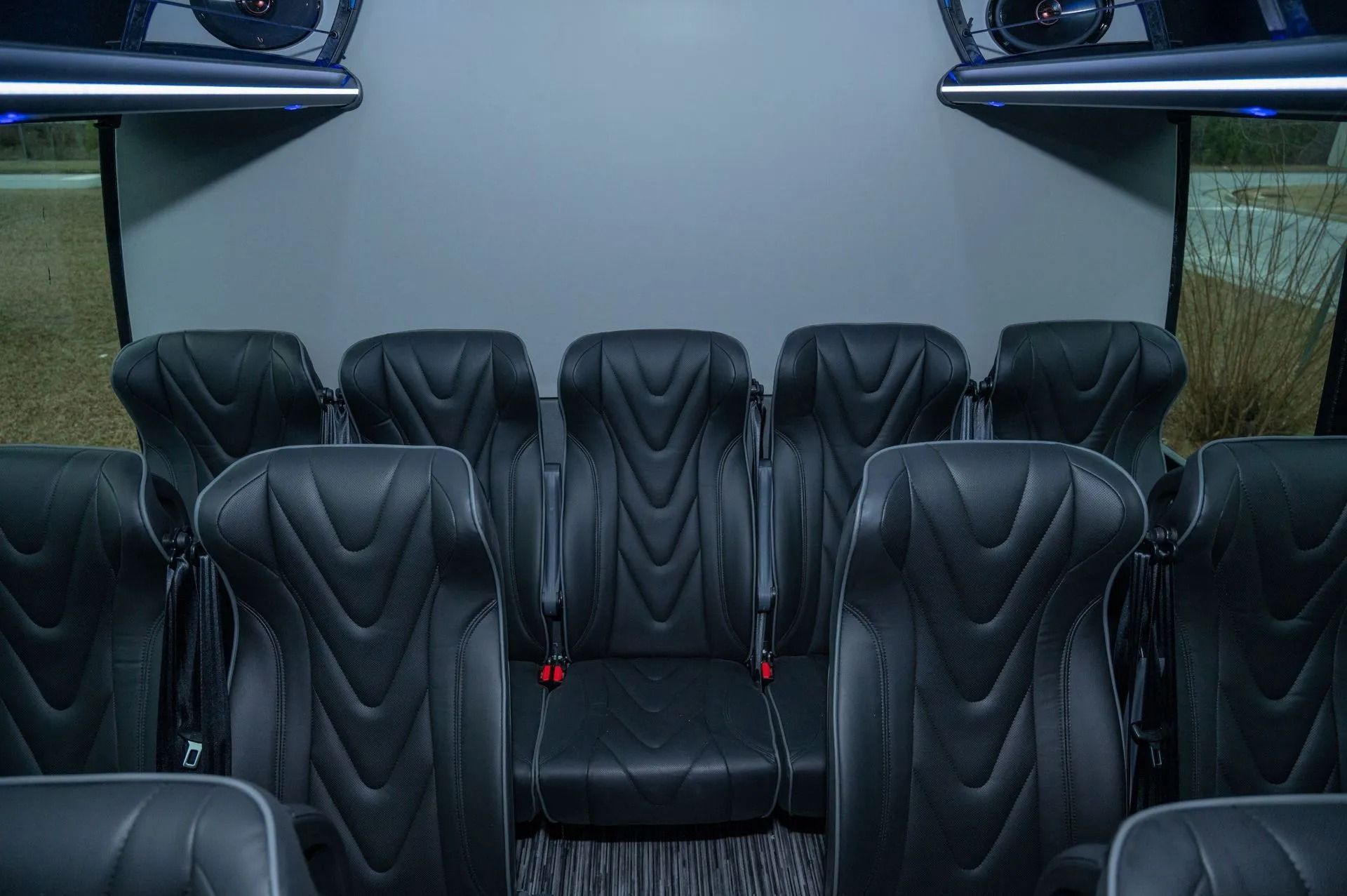 Interior of a vehicle featuring rows of black leather bucket seats with a textured, chevron-stitched design.