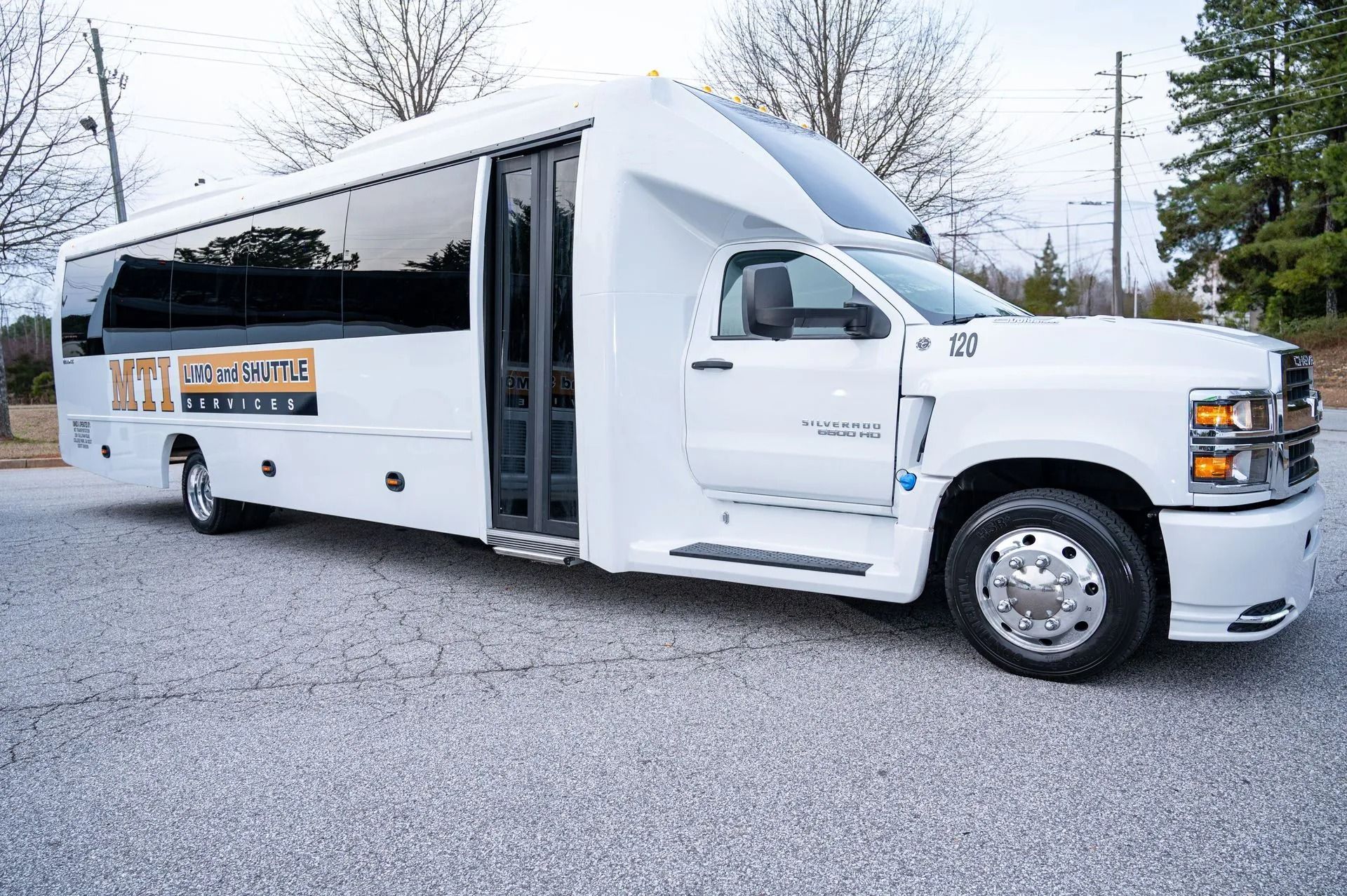 White shuttle bus with open door parked on a gravel lot outdoors