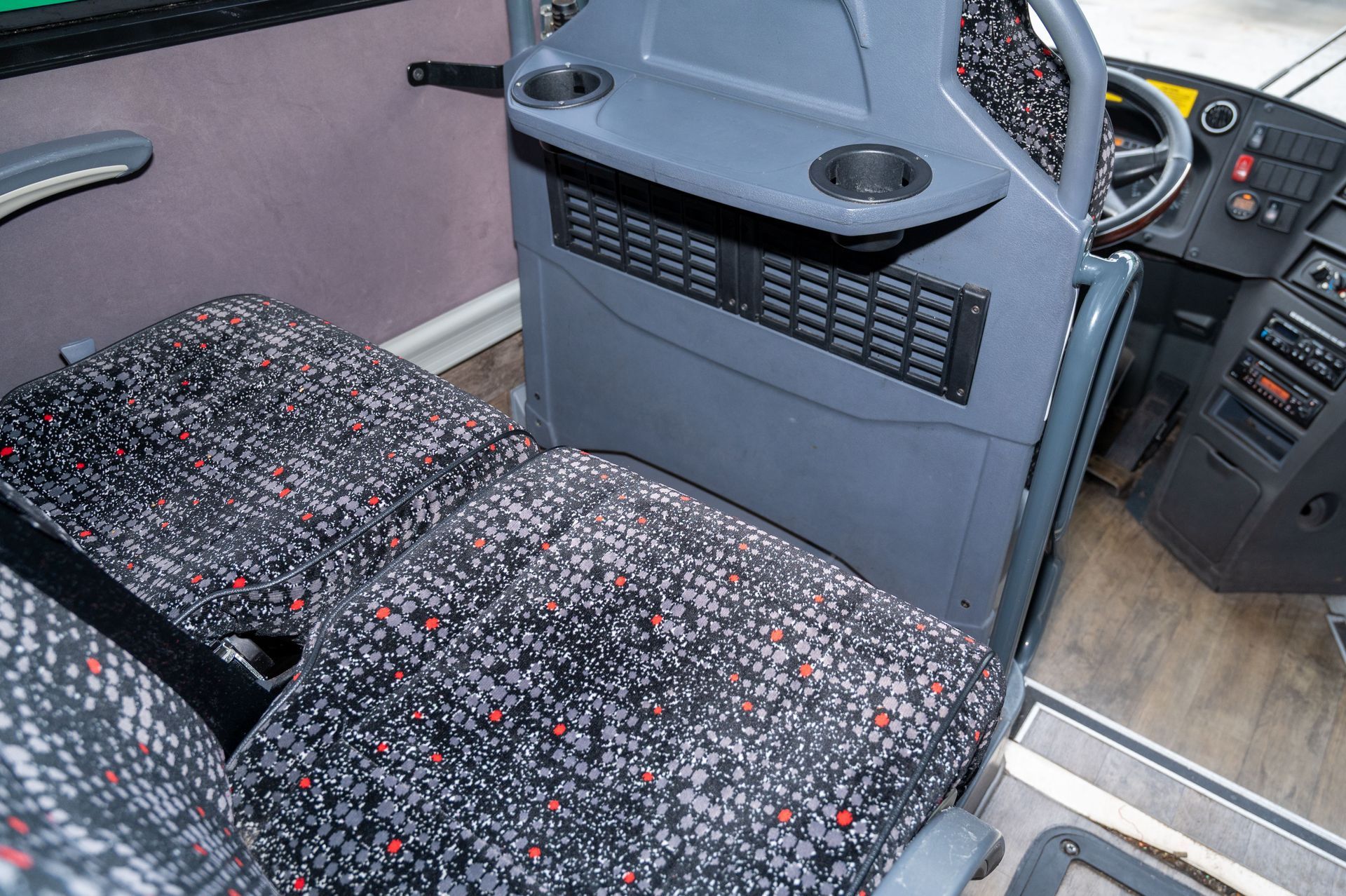 Bus interior with patterned fabric seats, aisle, and driver’s console area