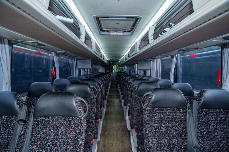Empty modern bus interior with rows of patterned seats and overhead lights