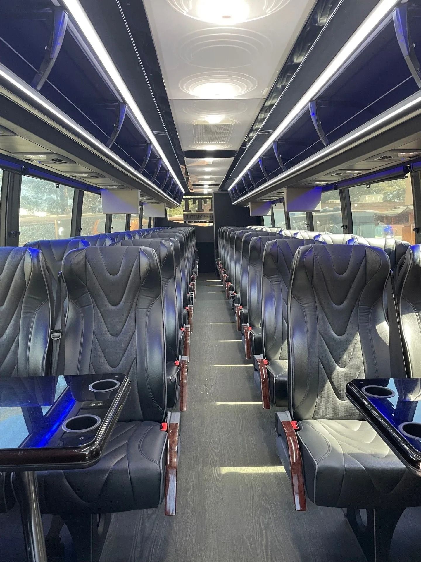 Empty luxury bus interior with blue-lit black seats and a central aisle