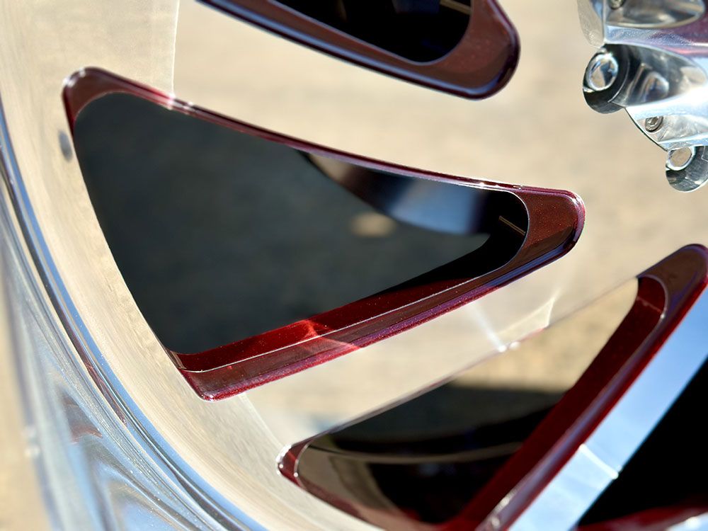 Close-up of a shiny, chrome car rim with dark red accents around the cut-out sections.