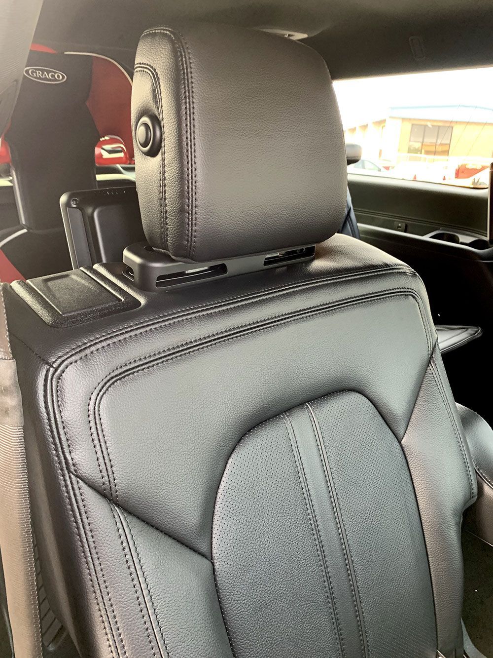 Black leather car seat with headrest and device mount.