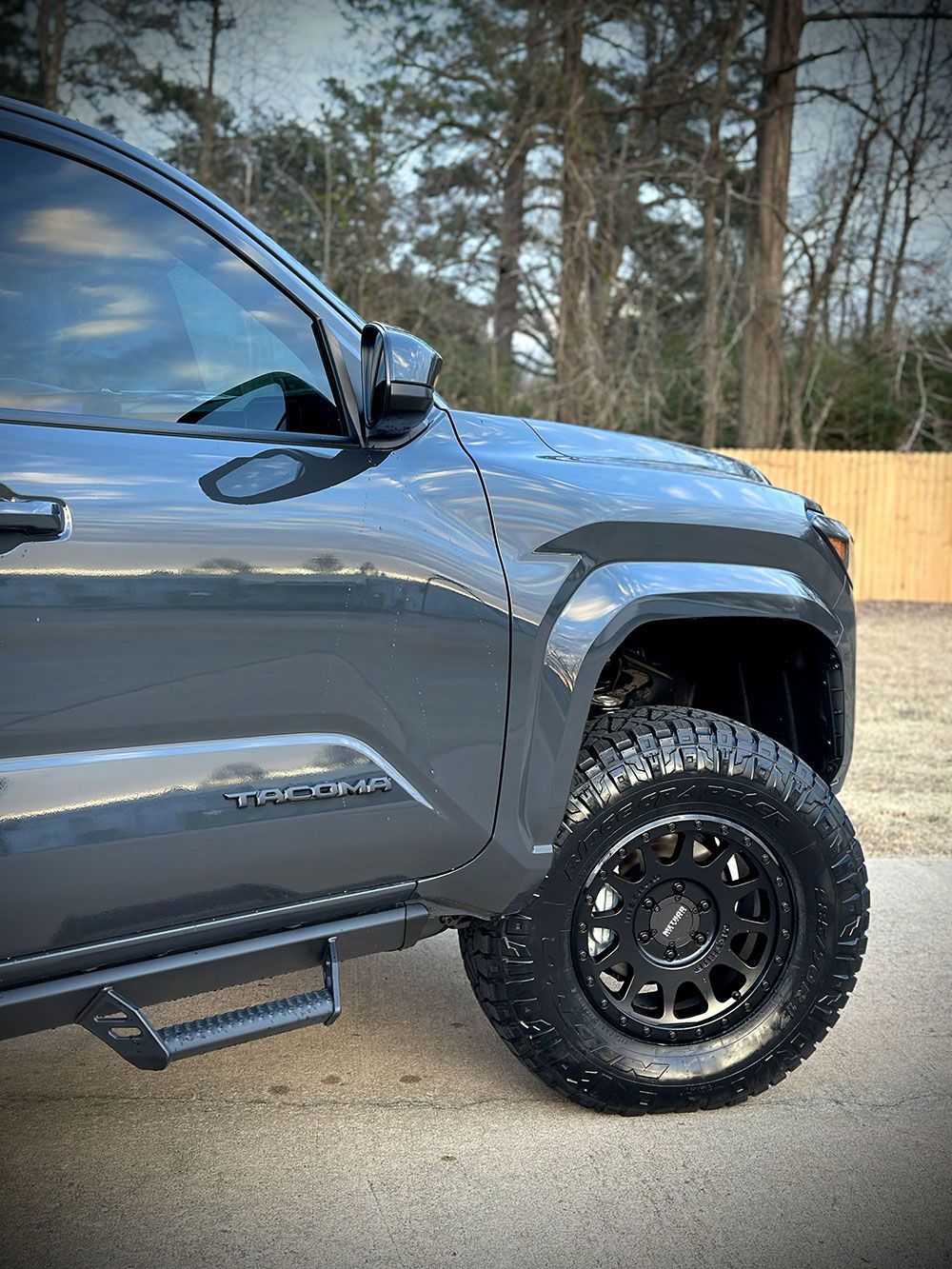 Dark gray Toyota Tundra truck with black off-road wheels and side steps. Parked outdoors.