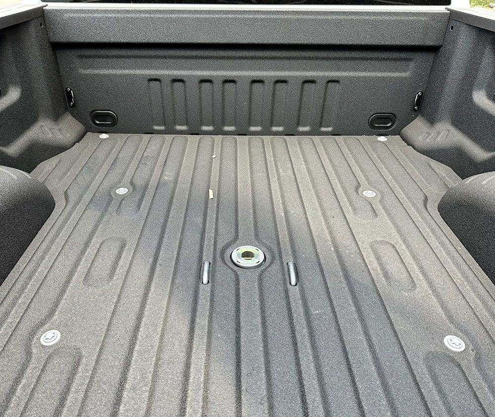 Truck bed with a textured black surface, including a gooseneck hitch.