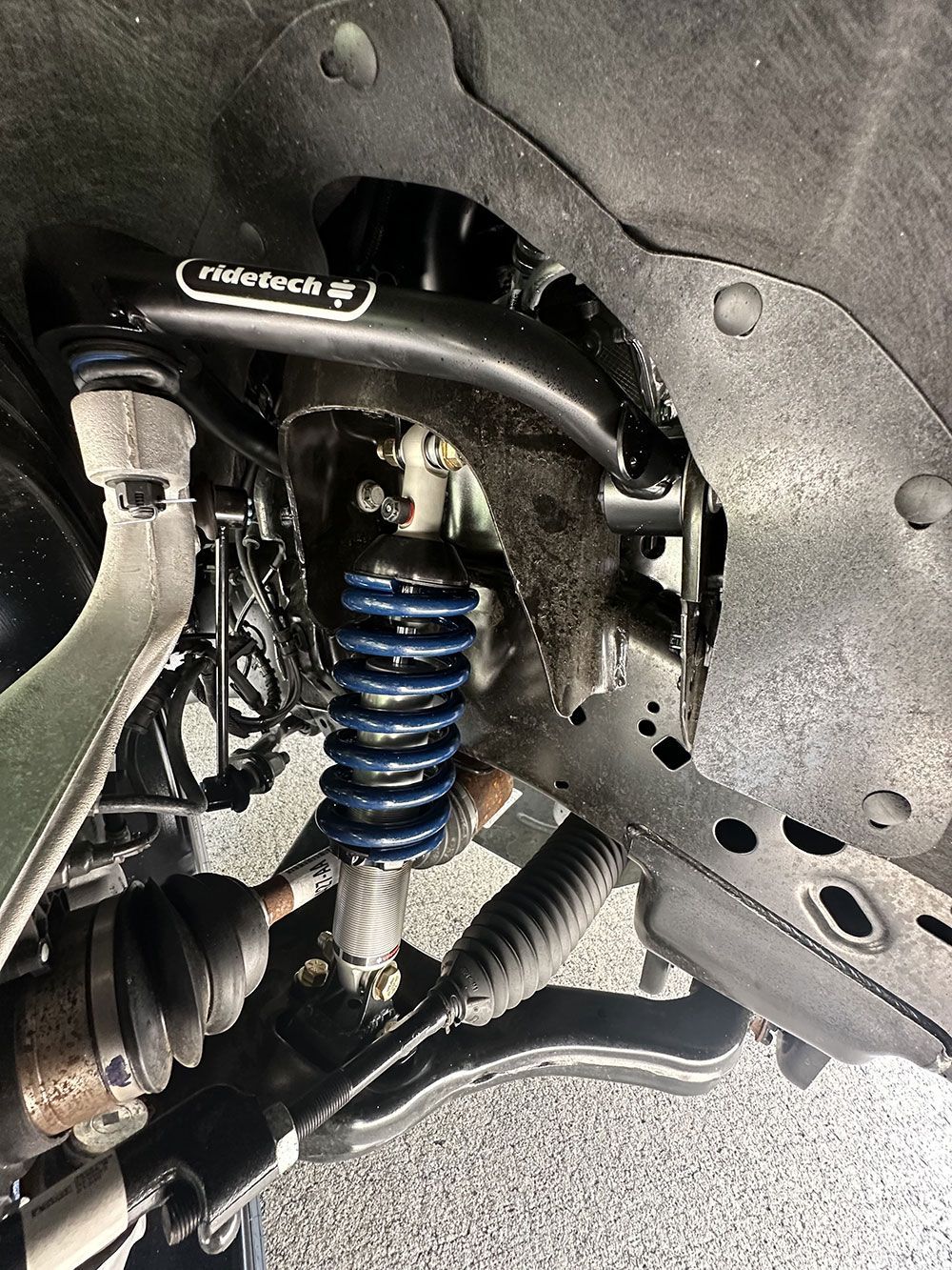 Black suspension components with a blue coil spring in an automobile.