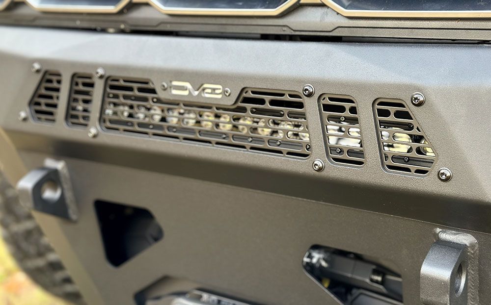 Close-up of a black metal car bumper with a light bar and air vents.