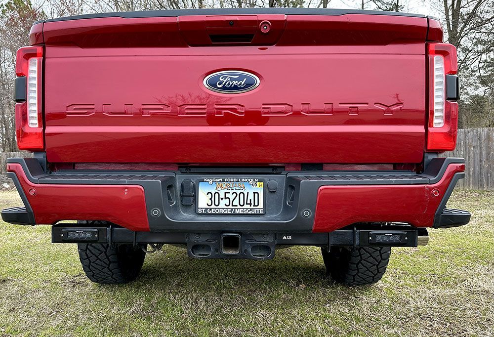 Rear view of a red Ford Super Duty truck with license plate, parked on grass.