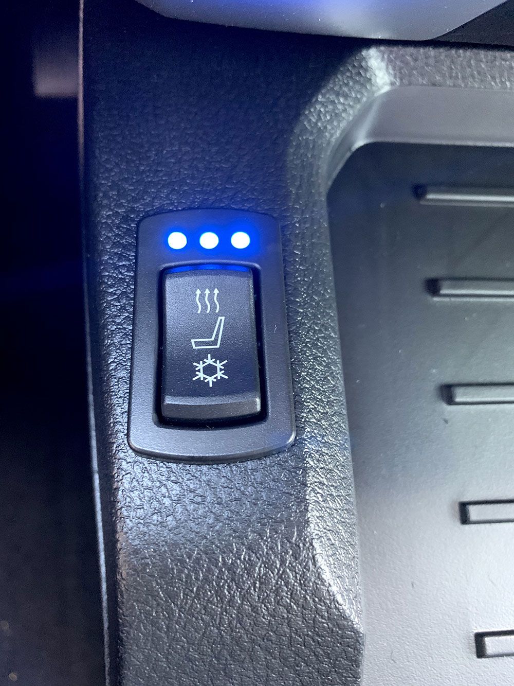 Car seat heater control switch with blue indicator lights.