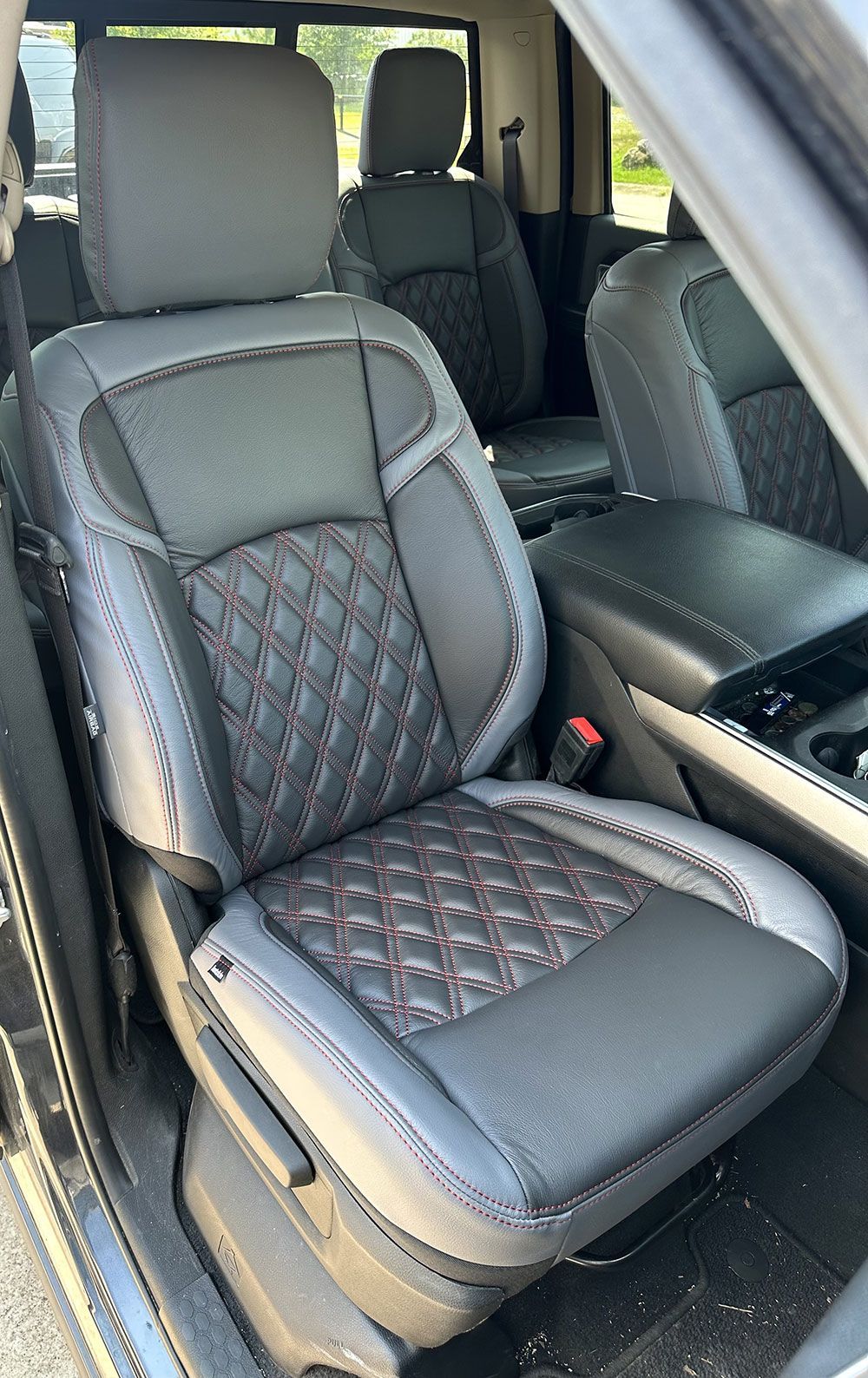 Gray and black car seat with diamond stitching, red thread details.