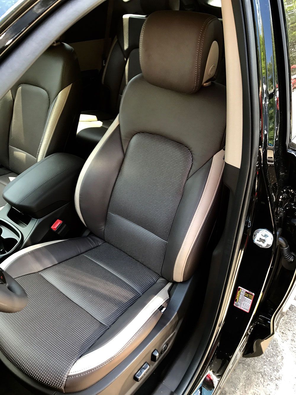 Black and tan car seat with textured center panel and adjustable features.