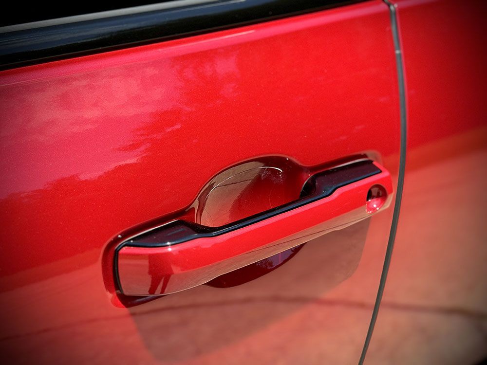 Red car door handle, black accents, close-up shot.