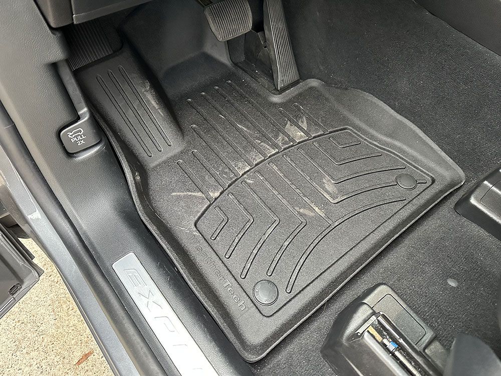 Black WeatherTech floor mat in a car, protecting carpet.