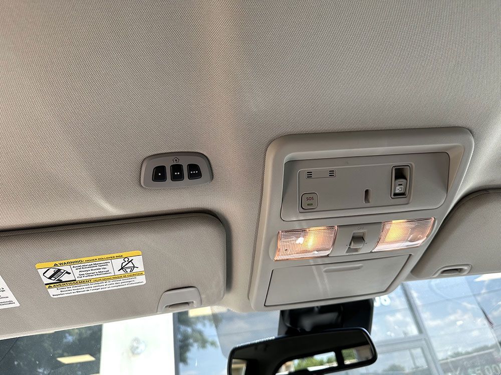 Interior car ceiling with garage door buttons, lights, sun visor, and rearview mirror.