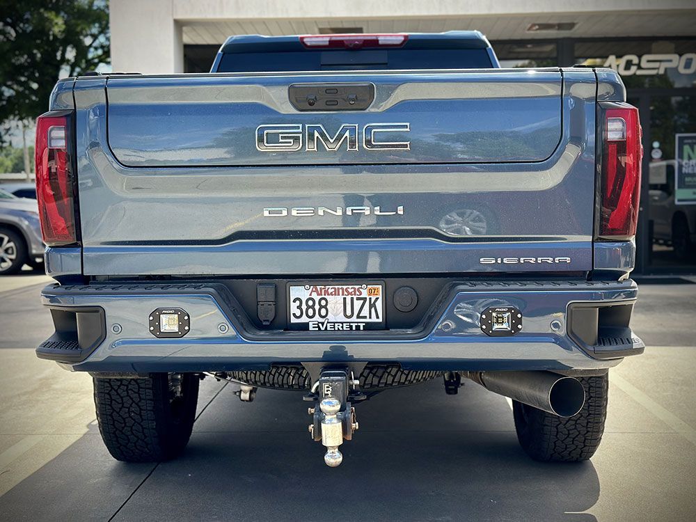 Rear view of a blue GMC Denali truck with aftermarket bumper, Utah license plate, and towing hitch.