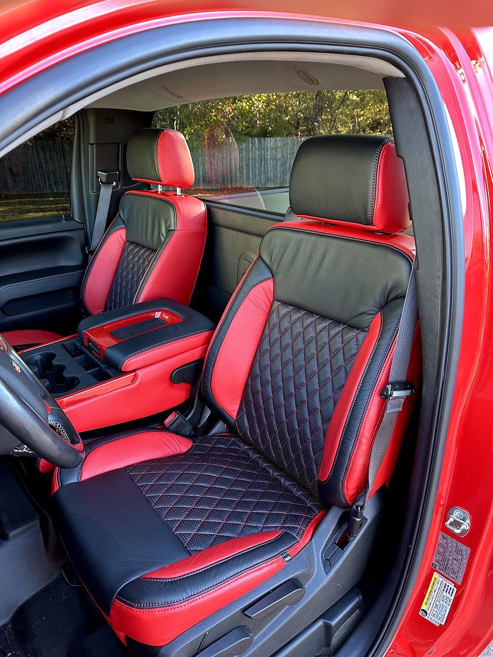 Red and black leather car seats with diamond stitching in a red vehicle.