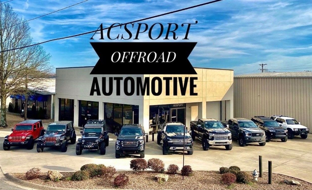 ACSport Offroad Automotive building with multiple off-road vehicles parked outside under a blue sky.