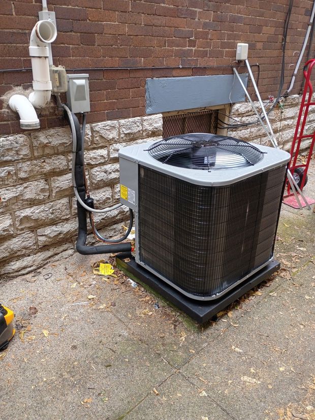 HVAC unit against a brick wall. Black grill and electrical components.