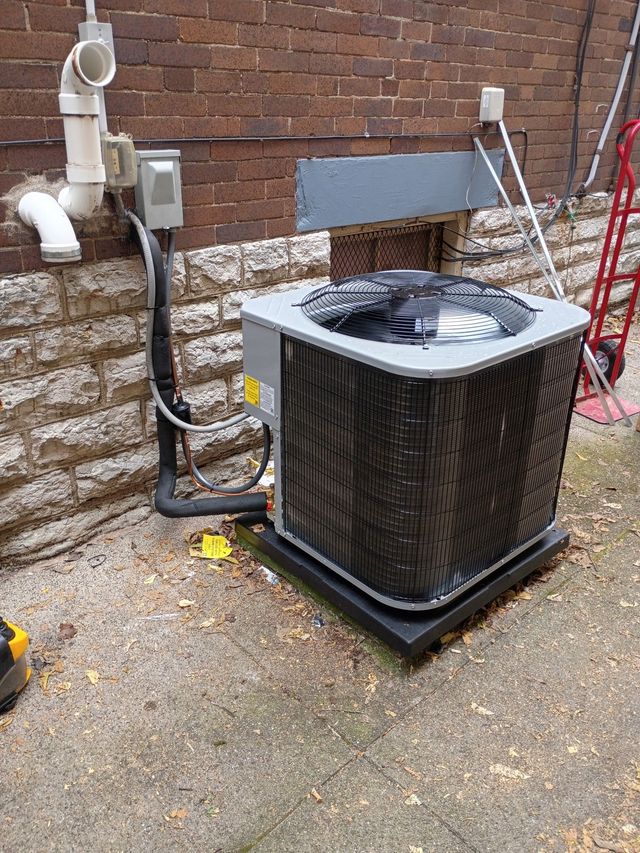HVAC unit against a brick wall. Black grill and electrical components.