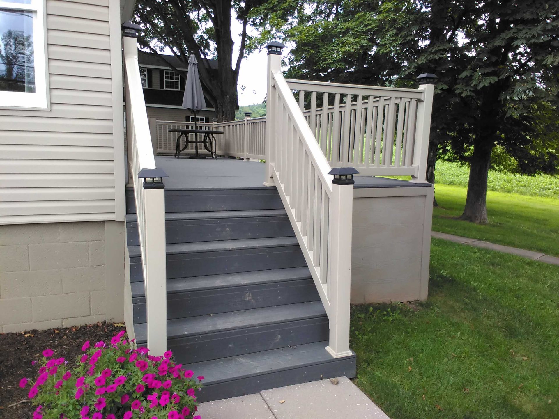 A house with stairs leading up to a deck with a picnic table