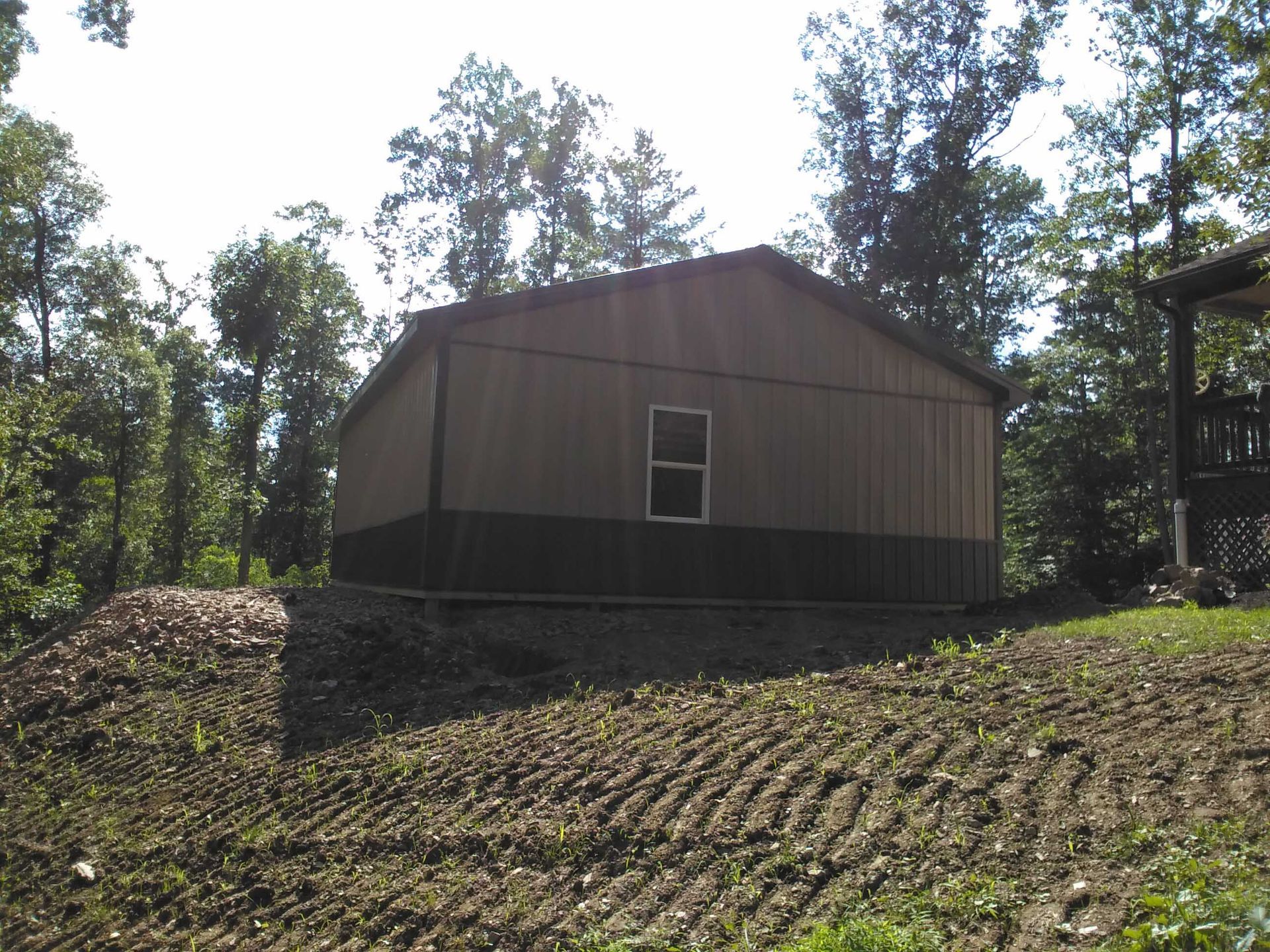 A brown building with a window sits in the middle of a dirt field