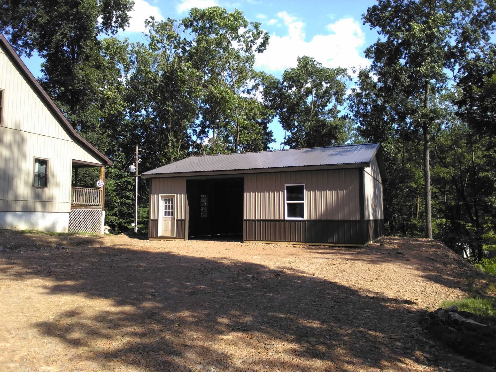 A garage with a black roof is surrounded by trees