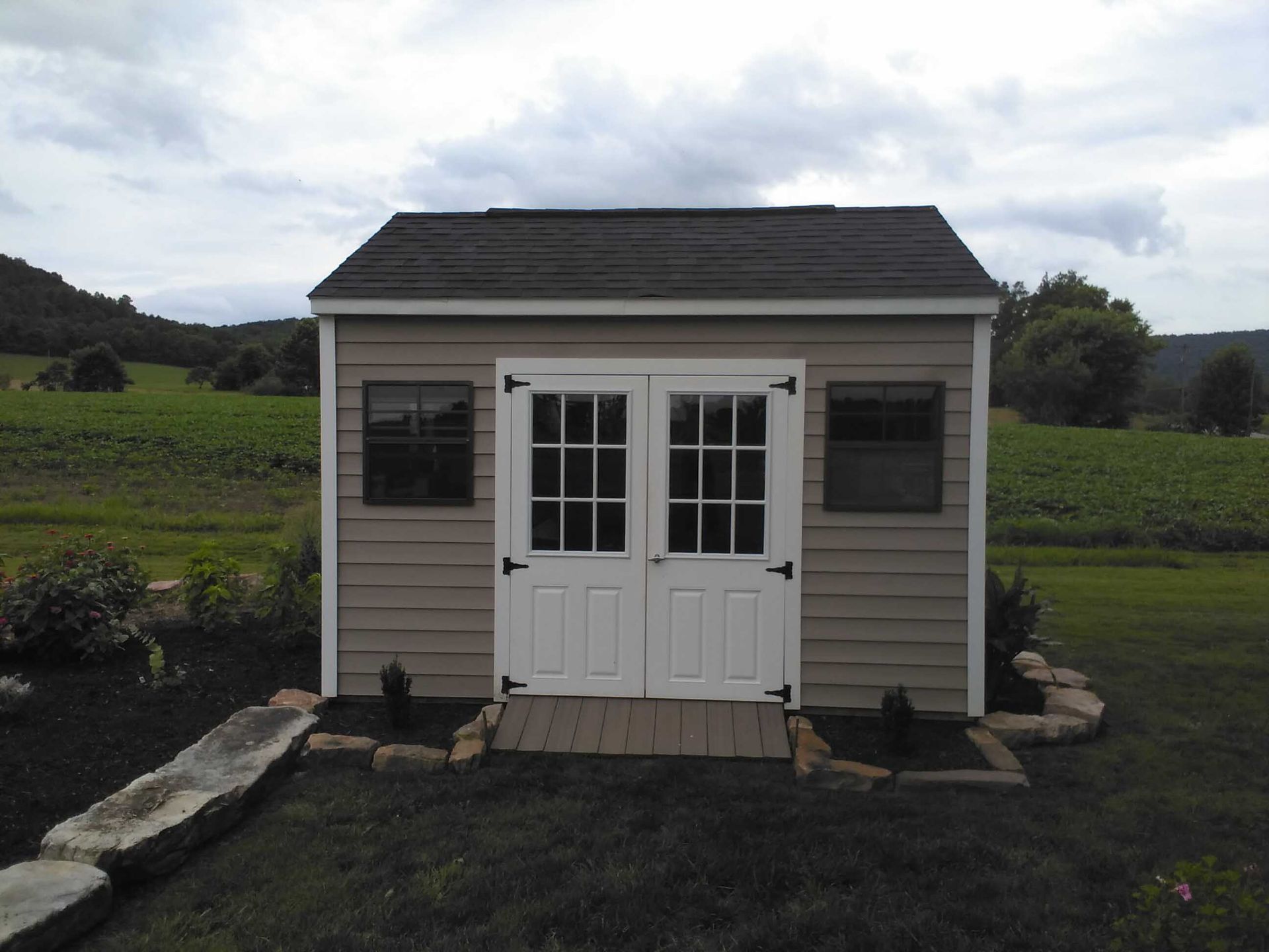 A small shed with a black roof and white doors