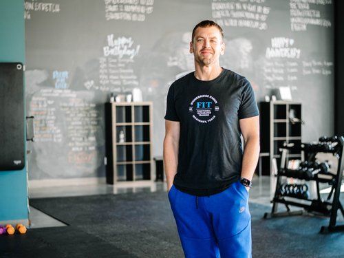 A man is standing in a gym with his hands in his pockets.