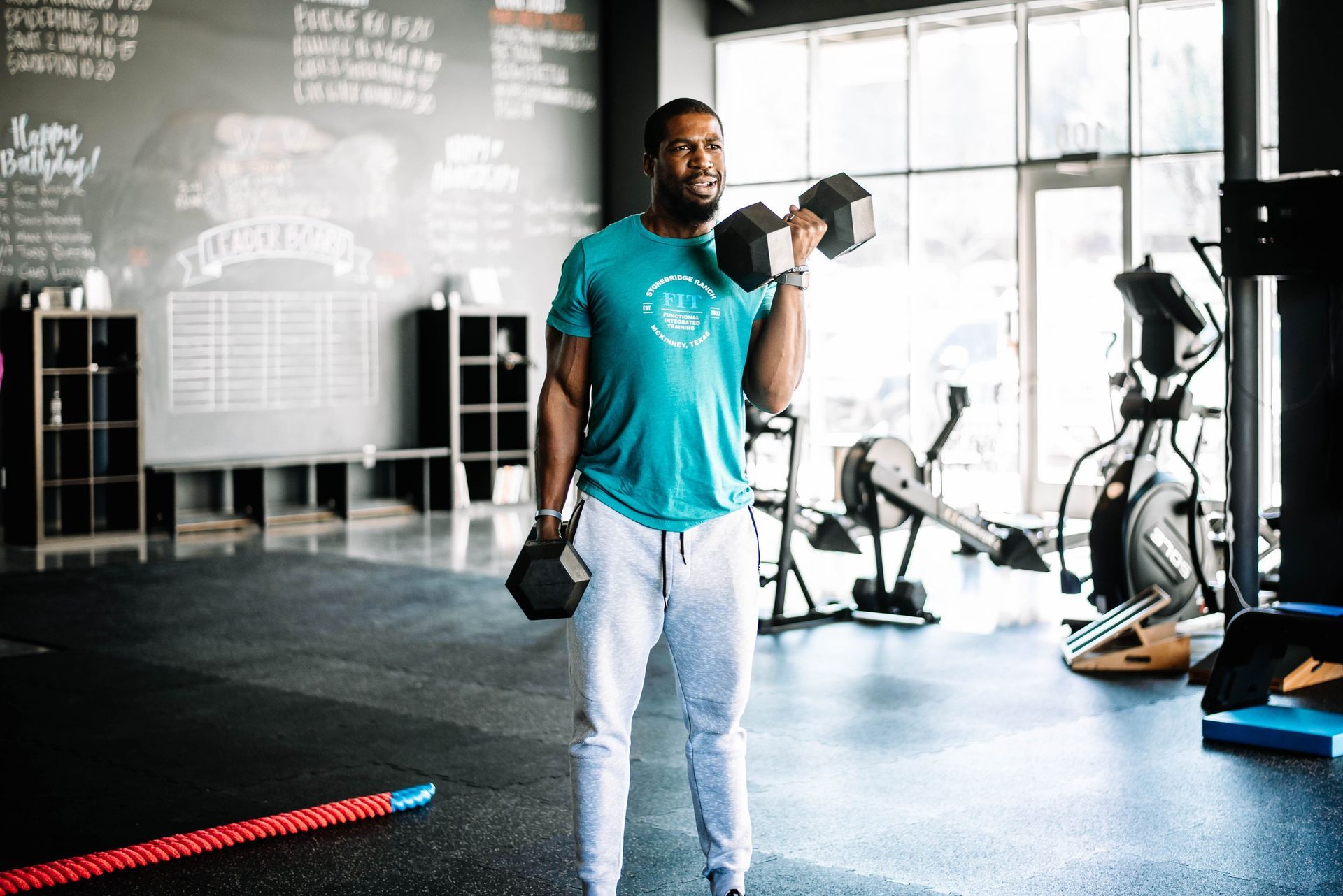 A man is lifting a dumbbell in a gym.