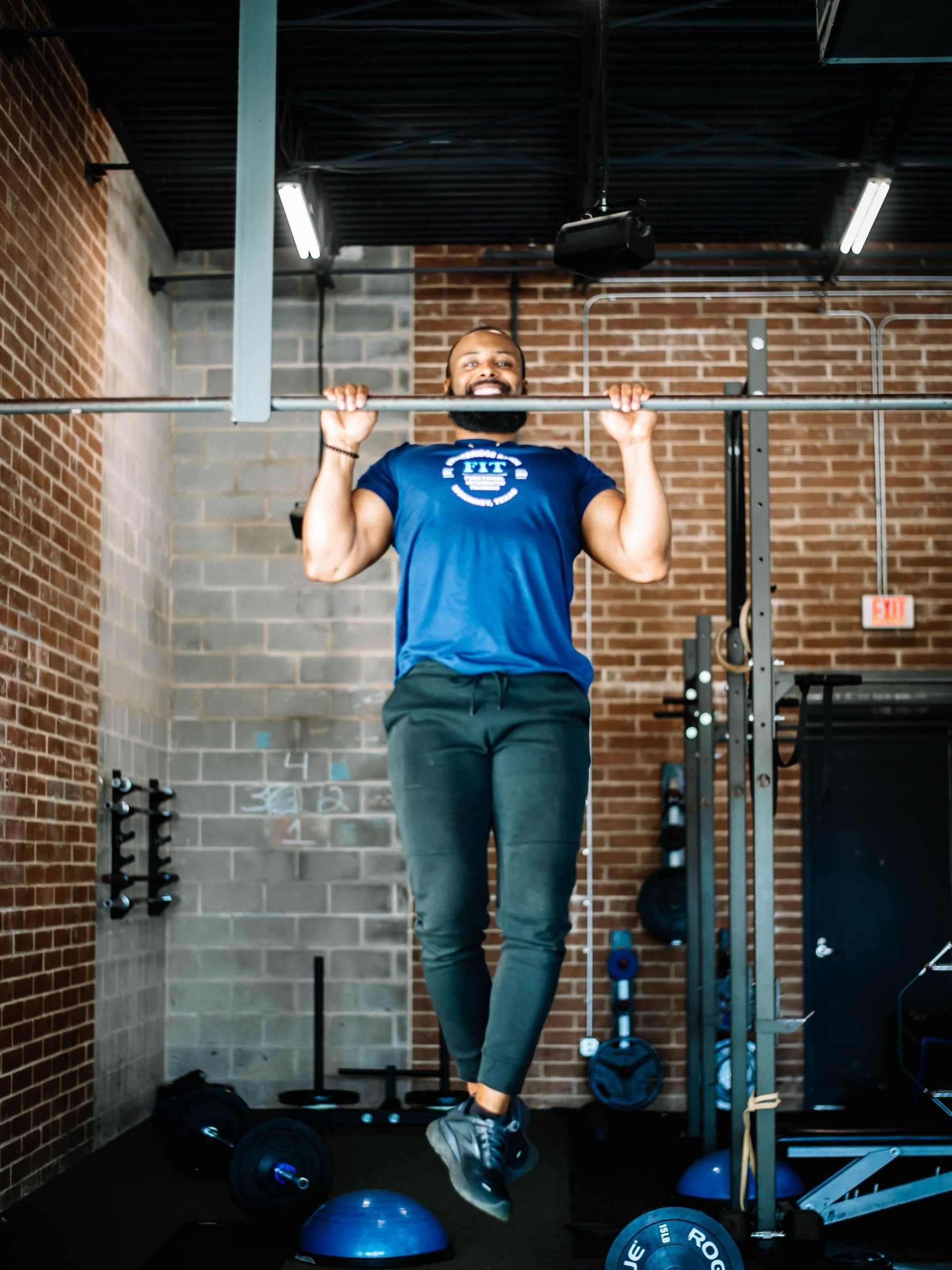 A man is doing pull ups on a bar in a gym.