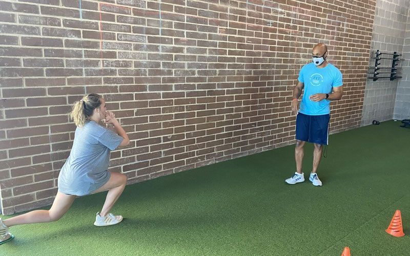 A man and a woman are doing exercises in a gym in front of a brick wall.