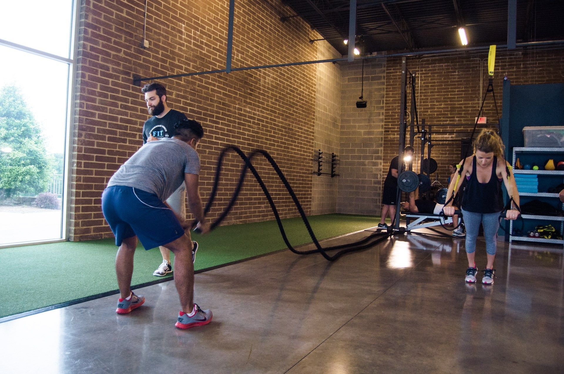 A group of people are doing exercises with ropes in a gym.