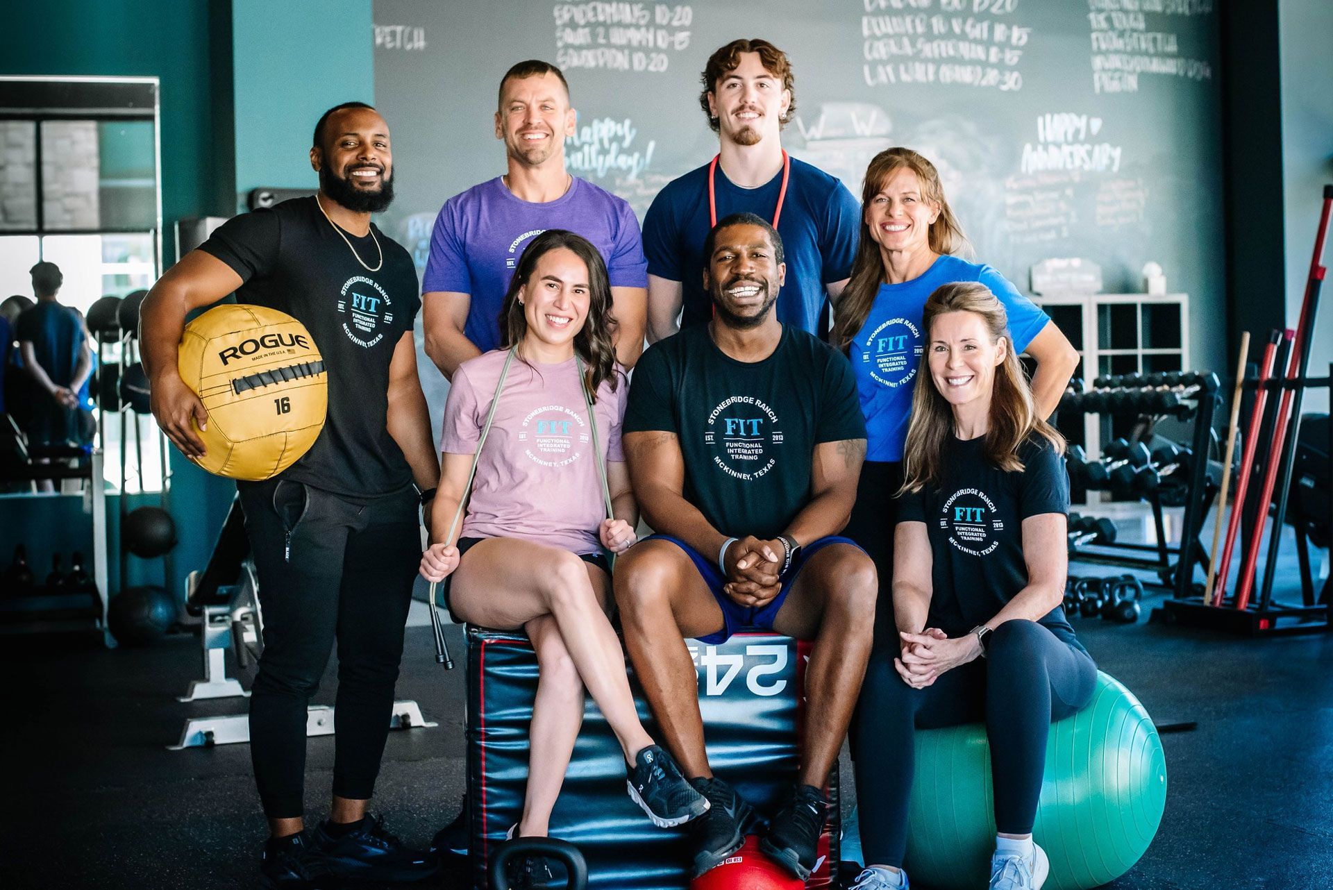 A group of people are posing for a picture in a gym.